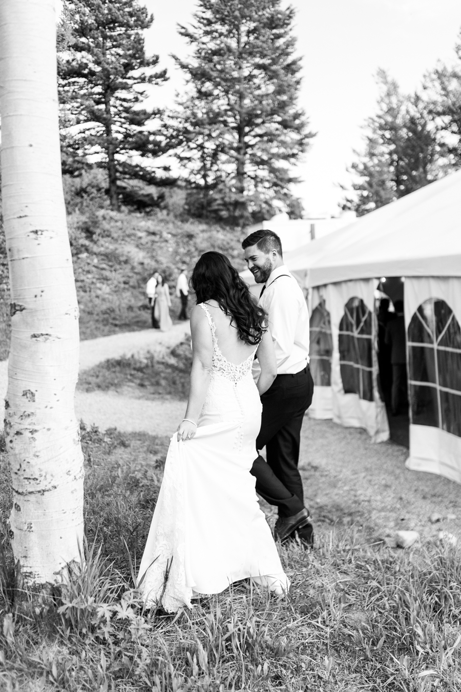A bride and groom enter their tented reception space in the Tetons