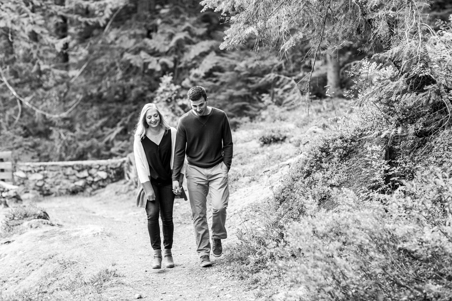 A couple strolls along a trail during their mountain engagement session in Leavenworth