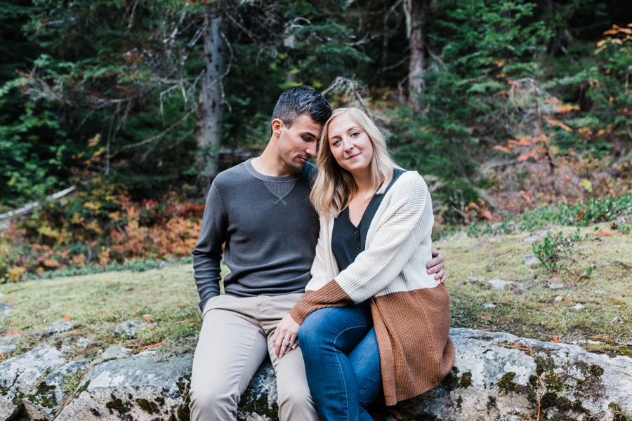 A couple enjoys each other's company while sitting on a rock near a trailhead by mountain wedding photographer Amy Galbraith