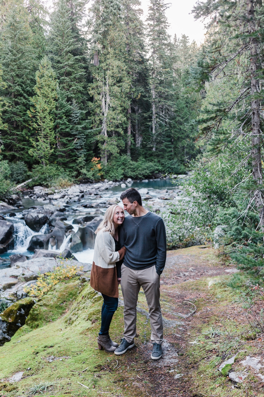 A couple takes engagement photos near a waterfall with mountain wedding photographer Amy Galbraith