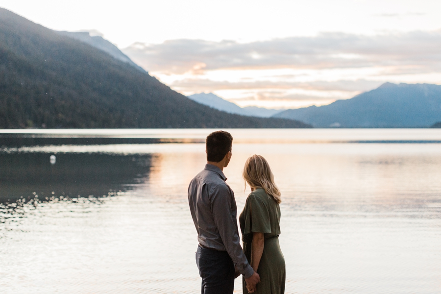 A couple watches the sunset on Lake Wenatchee for their mountain engagement session