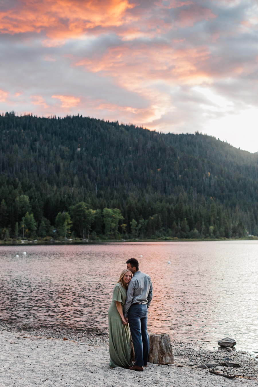 A bright orange sunset illuminates a couple during their mountain engagement photos at Lake Wenatchee by adventure wedding photographer Amy Galbraith