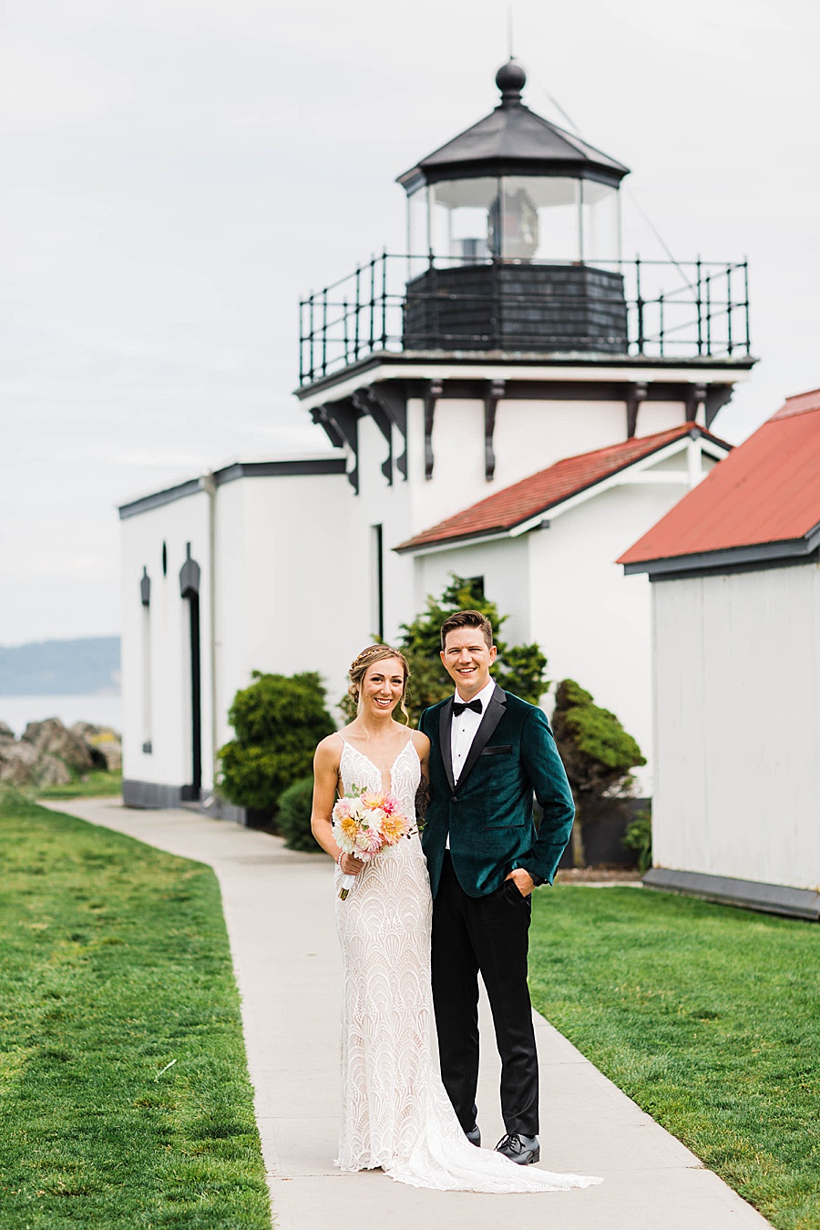 A bride and groom smile in front of Point No Point Lighthouse, photographed by Seattle wedding photographer Amy Galbraith