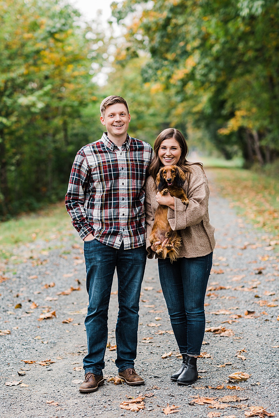 A couple snuggles their dog on a trail in North Bend, Washington during their engagement session