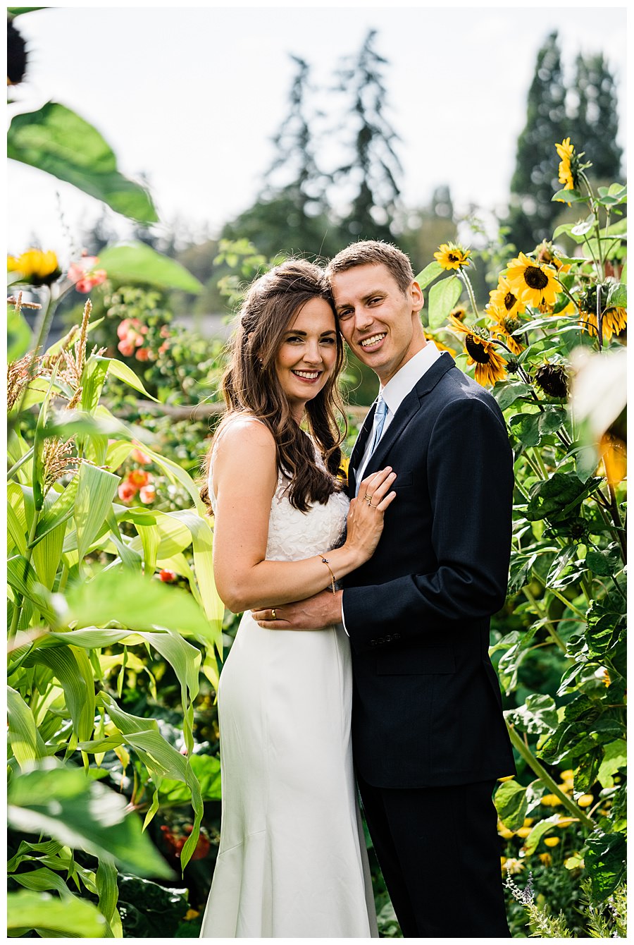 A bride and groom pose among the sunflowers during their Camano Island elopement photographed by Amy Galbraith