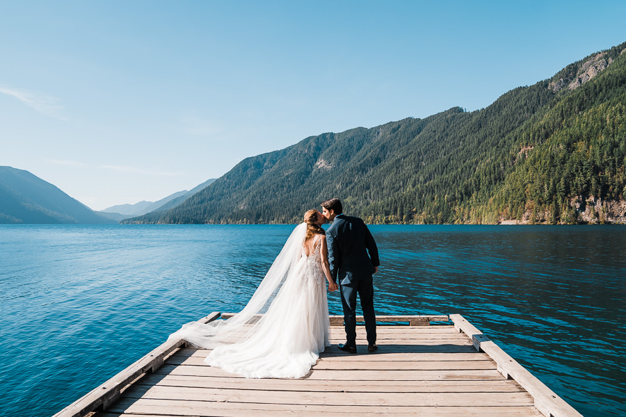 A couple kisses on the dock in front of Lake Crescent after eloping in Olympic National Park