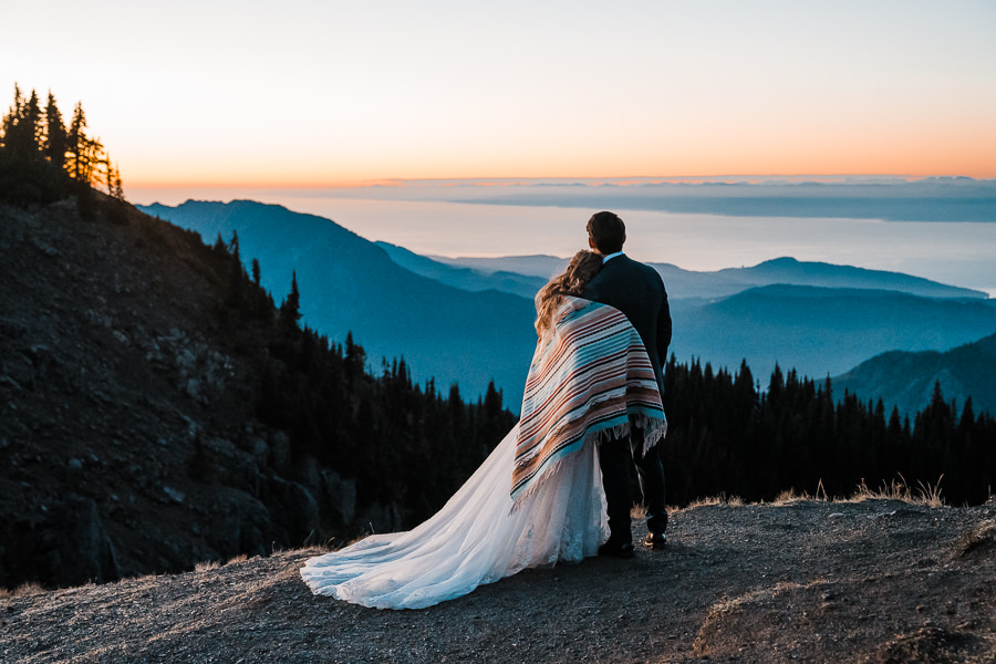 A couple snuggles under a Pendleton blanket while enjoying the view from Olympic National Park's Hurricane Ridge at dusk