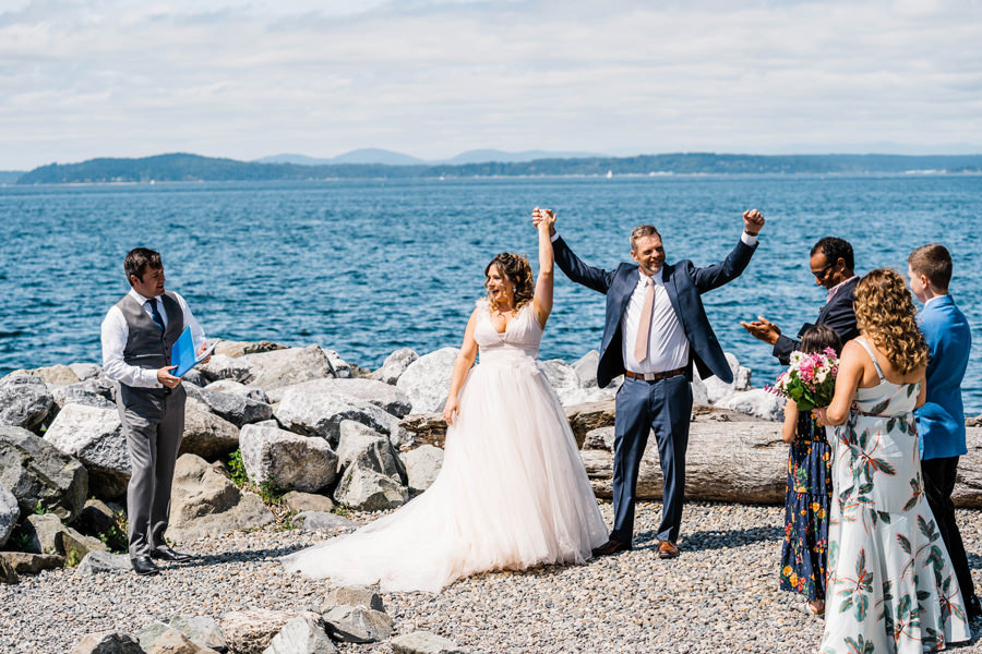 A couple celebrates right after they say their vows during their Seattle elopement with a small group of guests around them