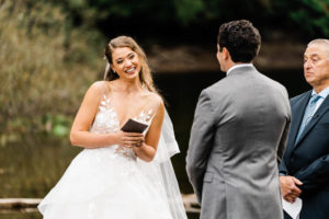 A bride smiles as she reads her vows to her groom during their elopement ceremony