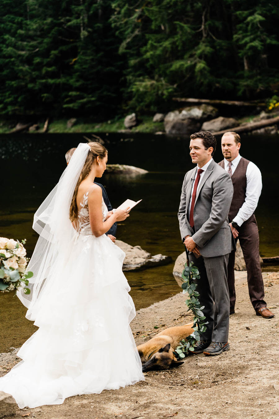 A groom smiles at his bride as she reads her vows to him