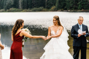 A friend passes the bride the wedding rings during the elopement ceremony