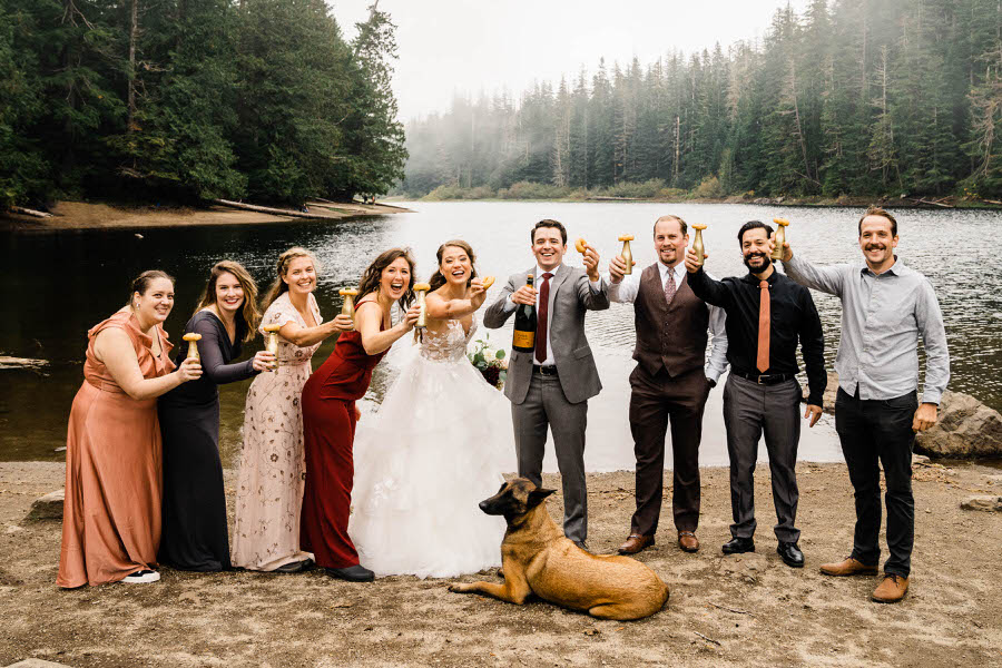 A bride and groom toast with champagne and doughnuts in the Washington backcountry after their hiking elopement