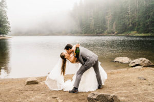 A groom dips his bride after they toast champagne in the Washington backcrountry
