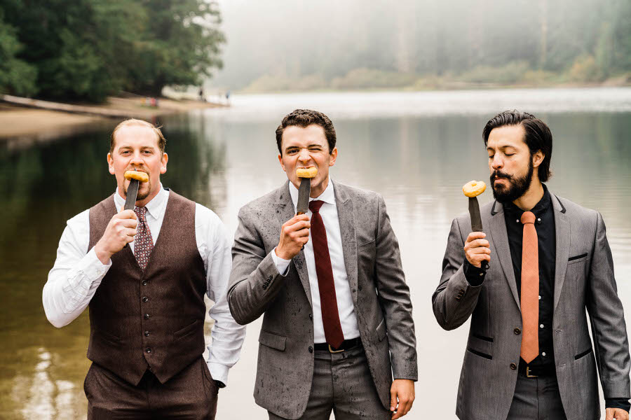 A groom eats doughnuts with his groomsmen at a hiking elopement in the Washington Cascades