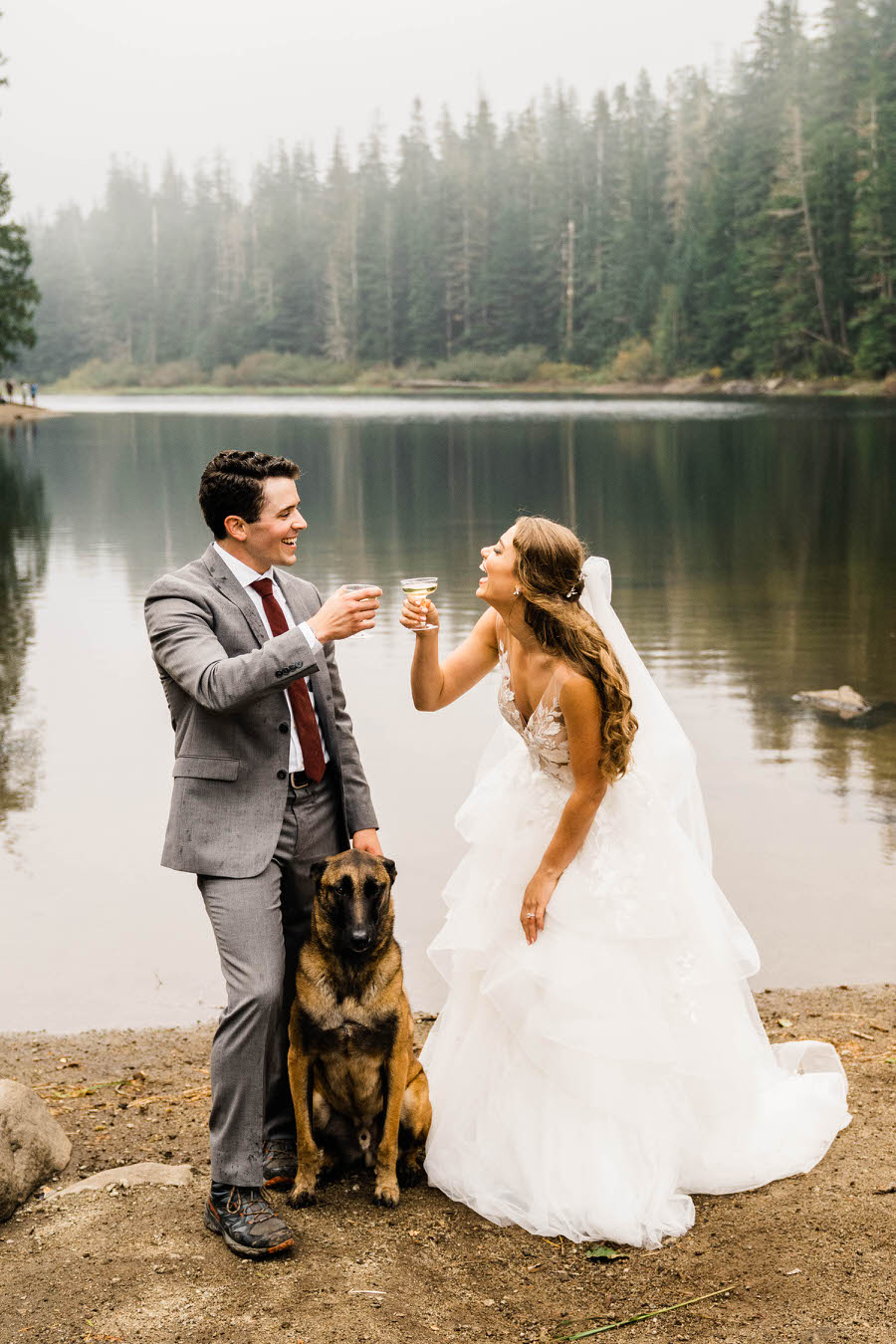 A bride and groom toast champagne as their dog stands with them after their hiking elopement in Washington
