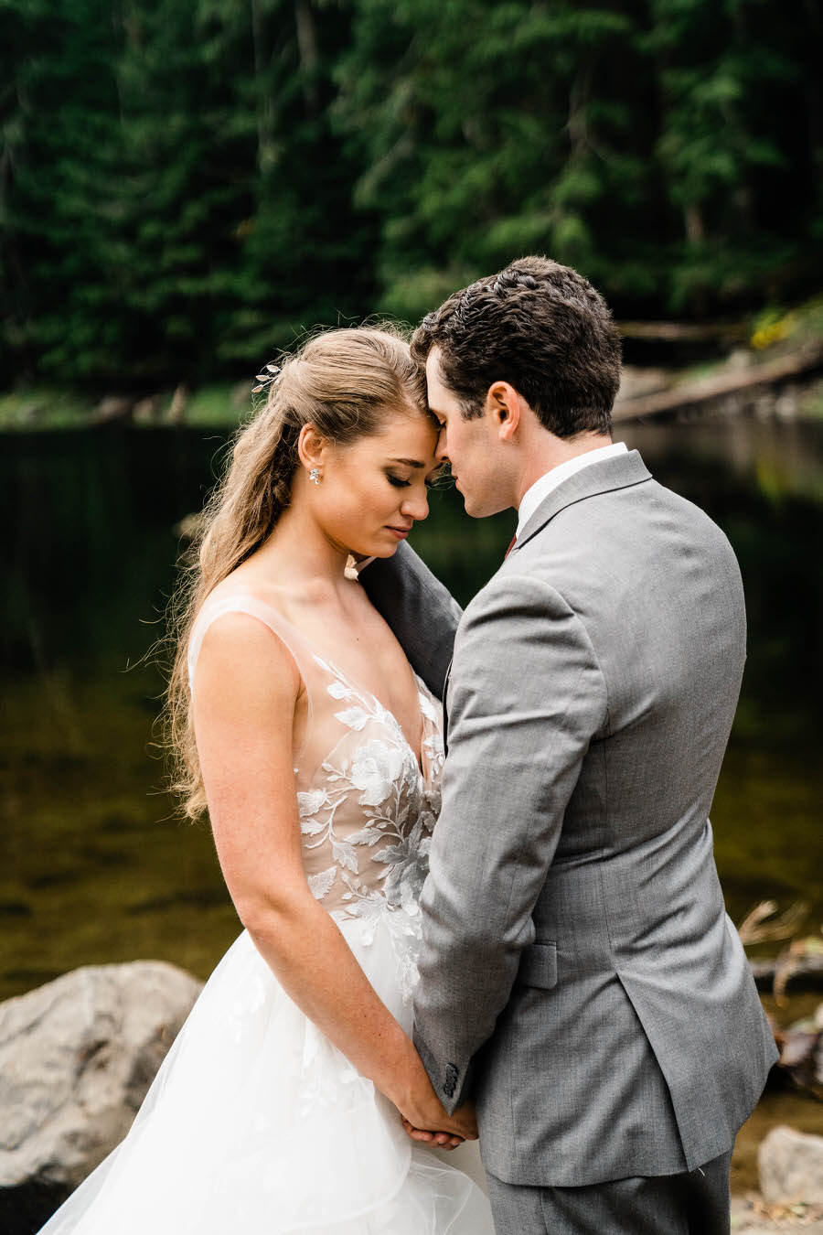 A bride and groom share a quiet moment together next to an alpine lake after their hiking elopement in the Washington backcountry