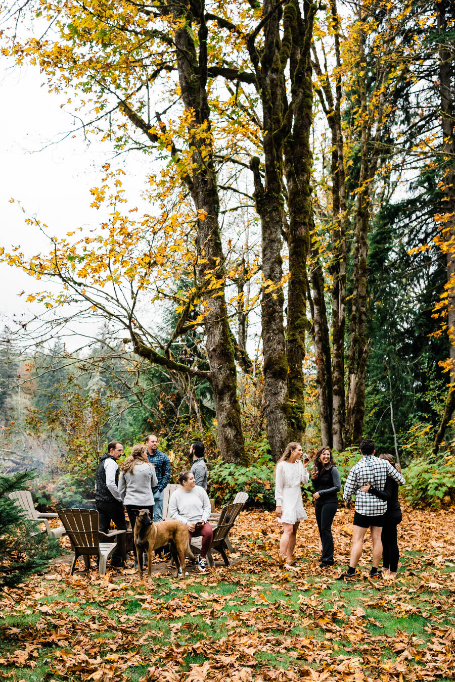 Elopement guests enjoy socializing by an outdoor fire pit in the fall