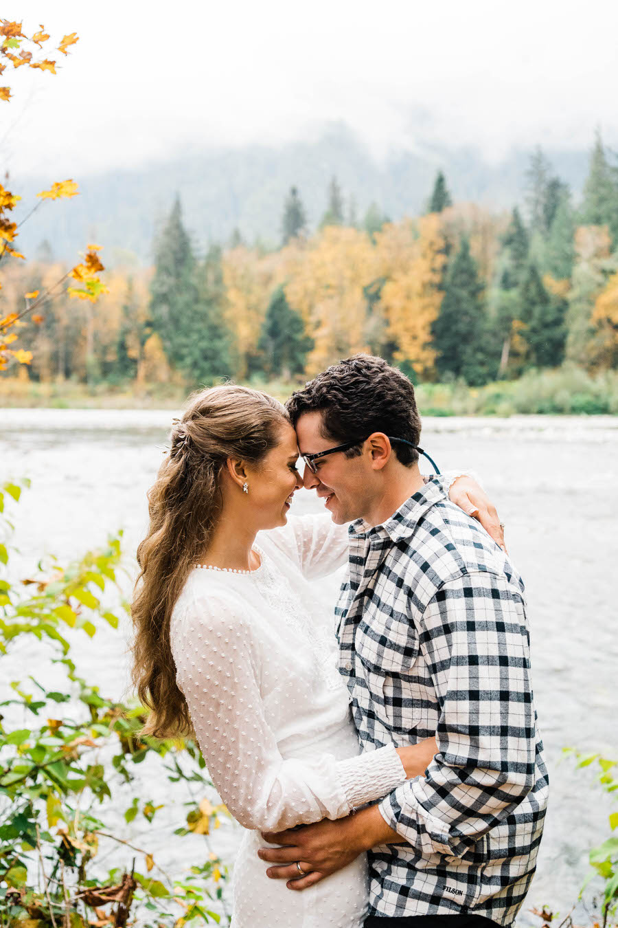 A bride and groom share a fun moment together by the river at their cabin after their hiking elopement
