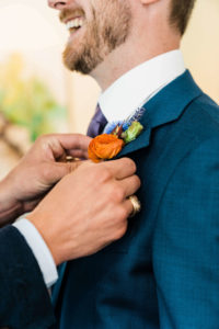 Orange flower on groom's blue suit