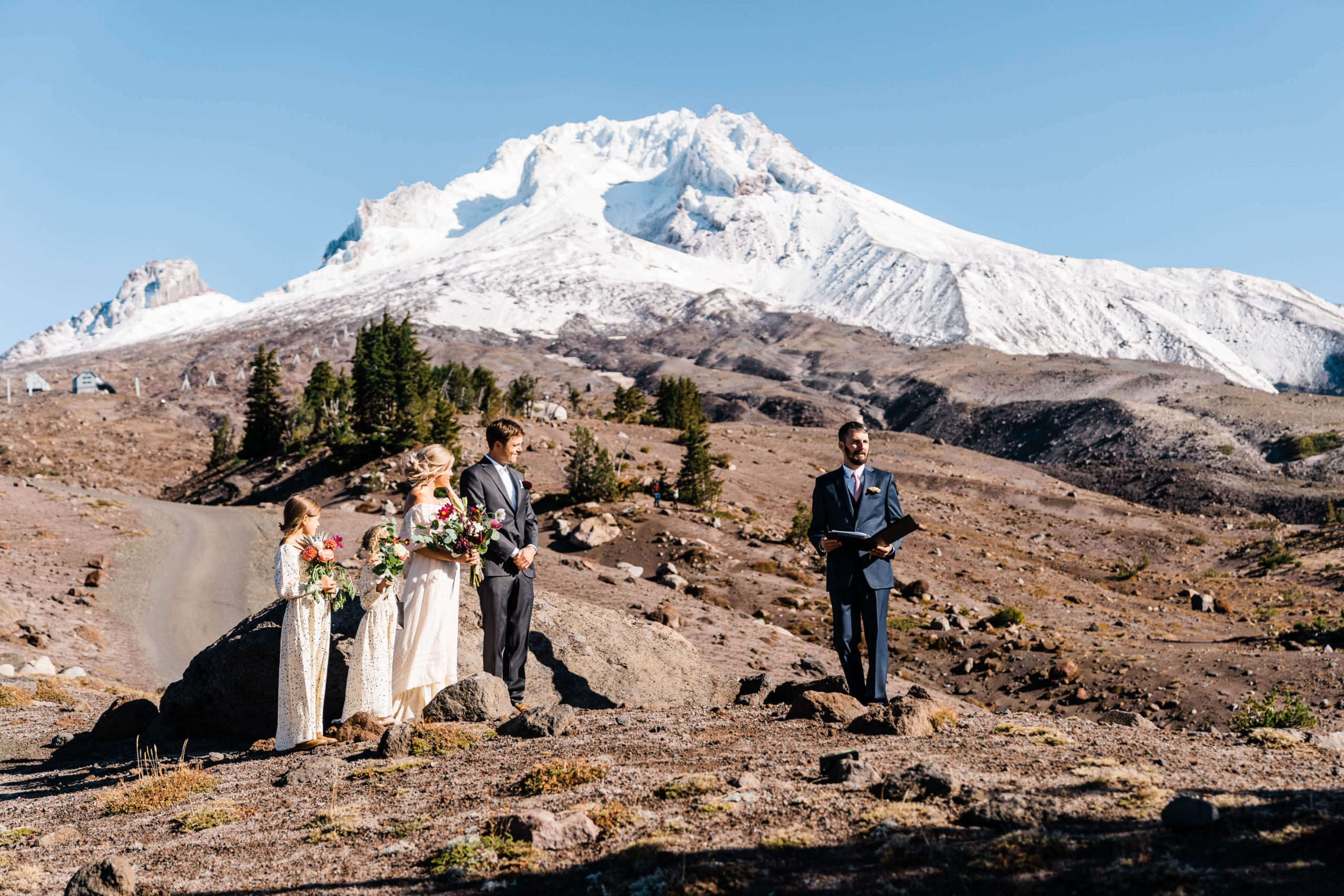 wedding ceremony with flower girls at the base of a snowy mountain
