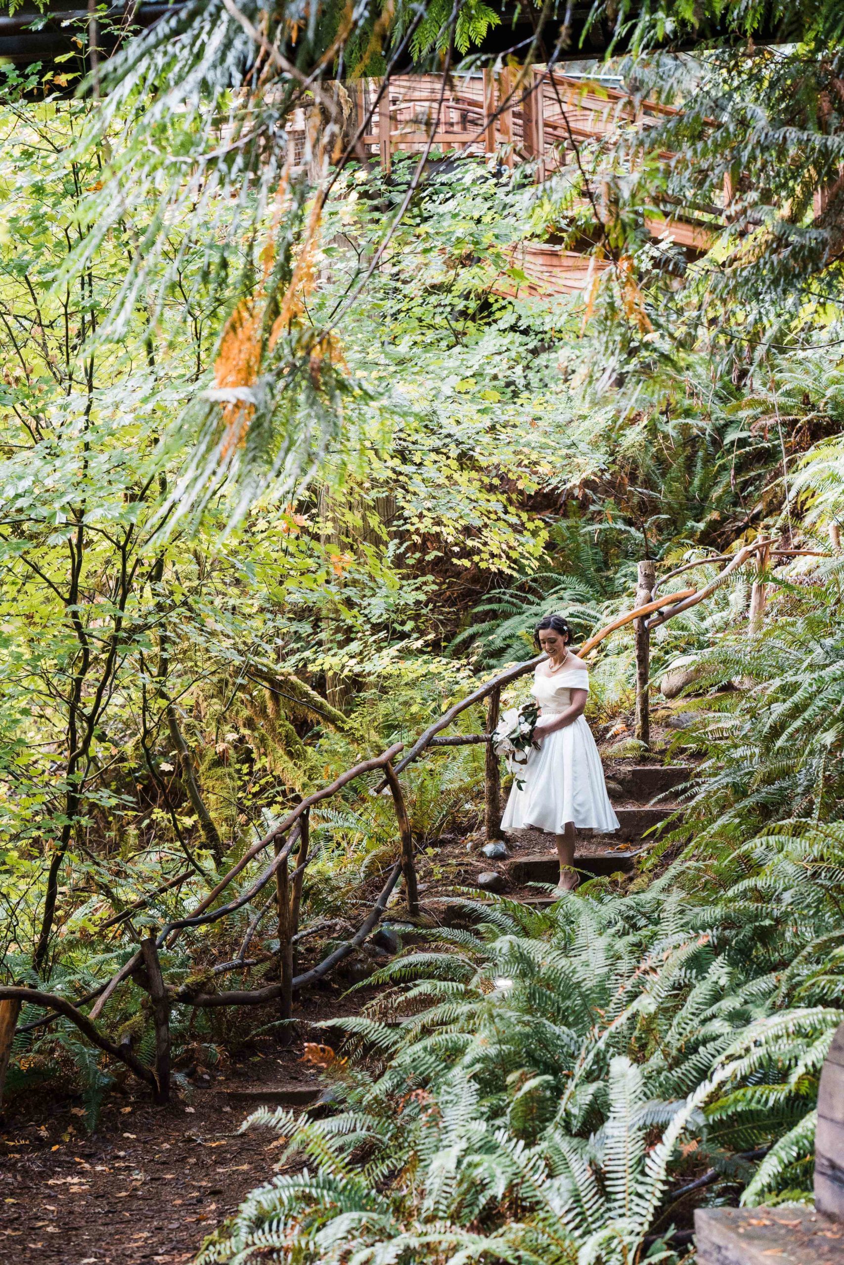Bride walking down stairs in the forest for her Treehouse Point wedding ceremony