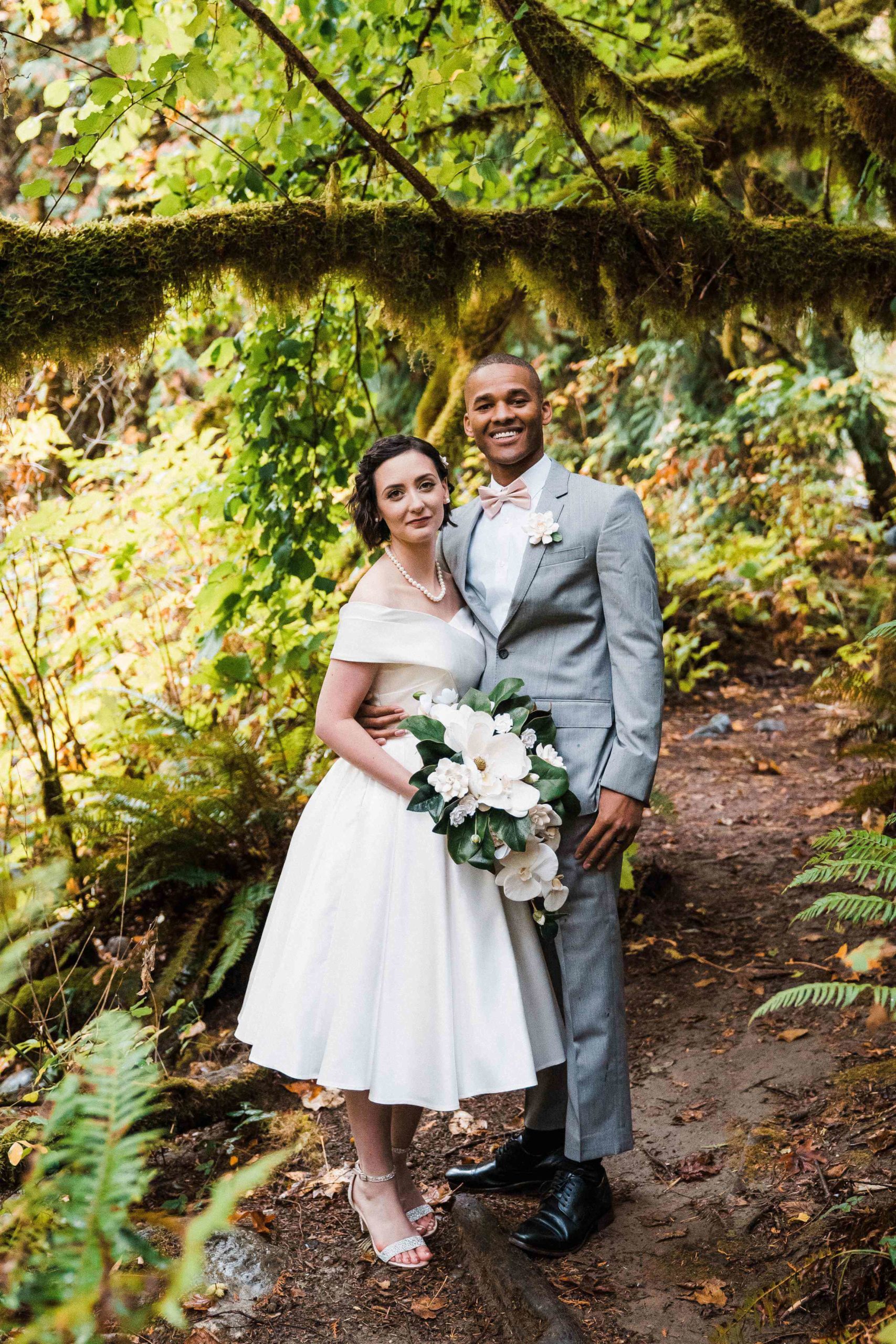 Bride and groom standing on a forest trail for their forest elopement
