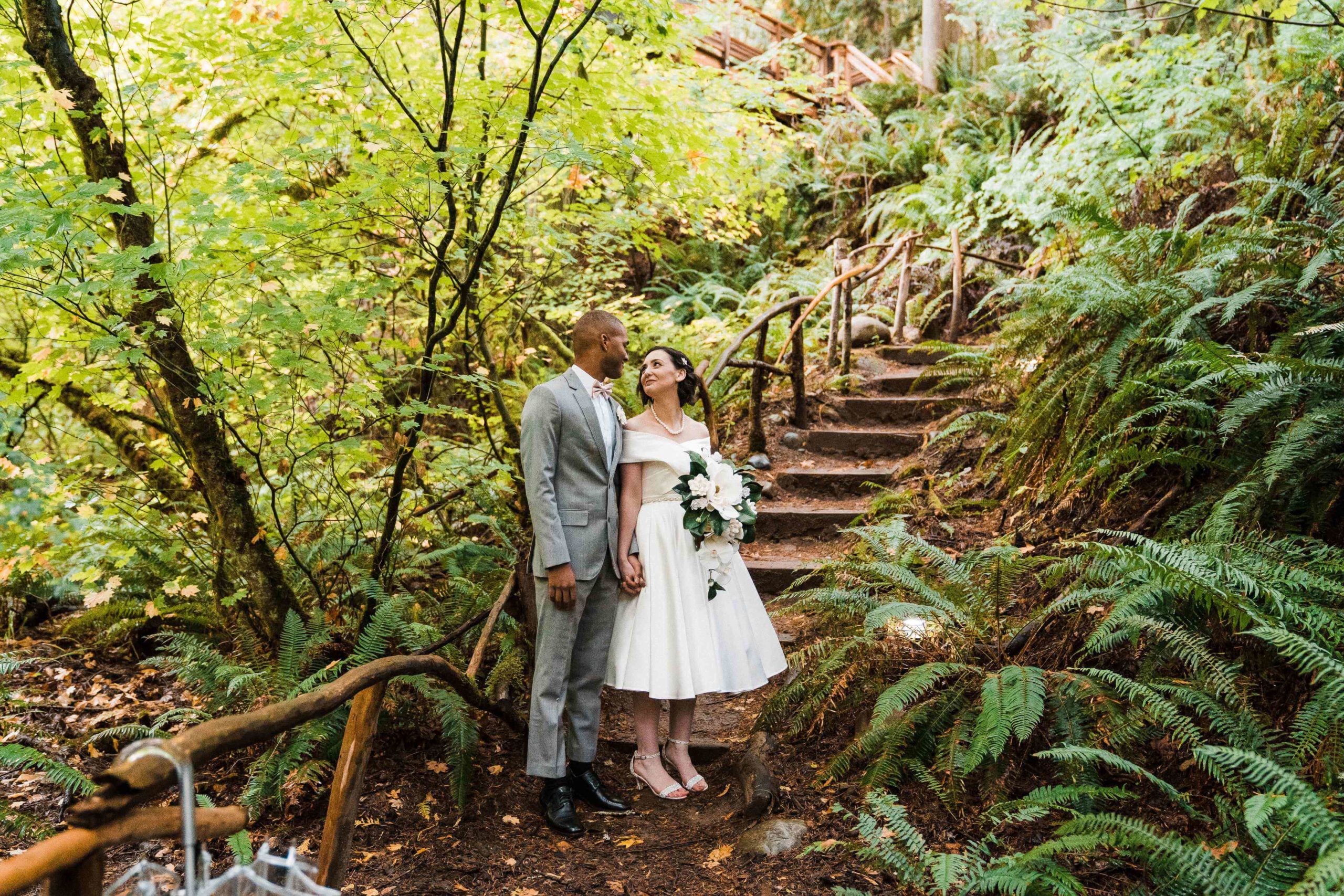 Bride and groom standing on steps in the forest for their couple photos