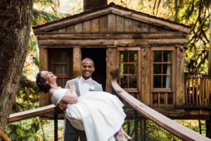 Groom carrying bride across the bridge at Treehouse Point