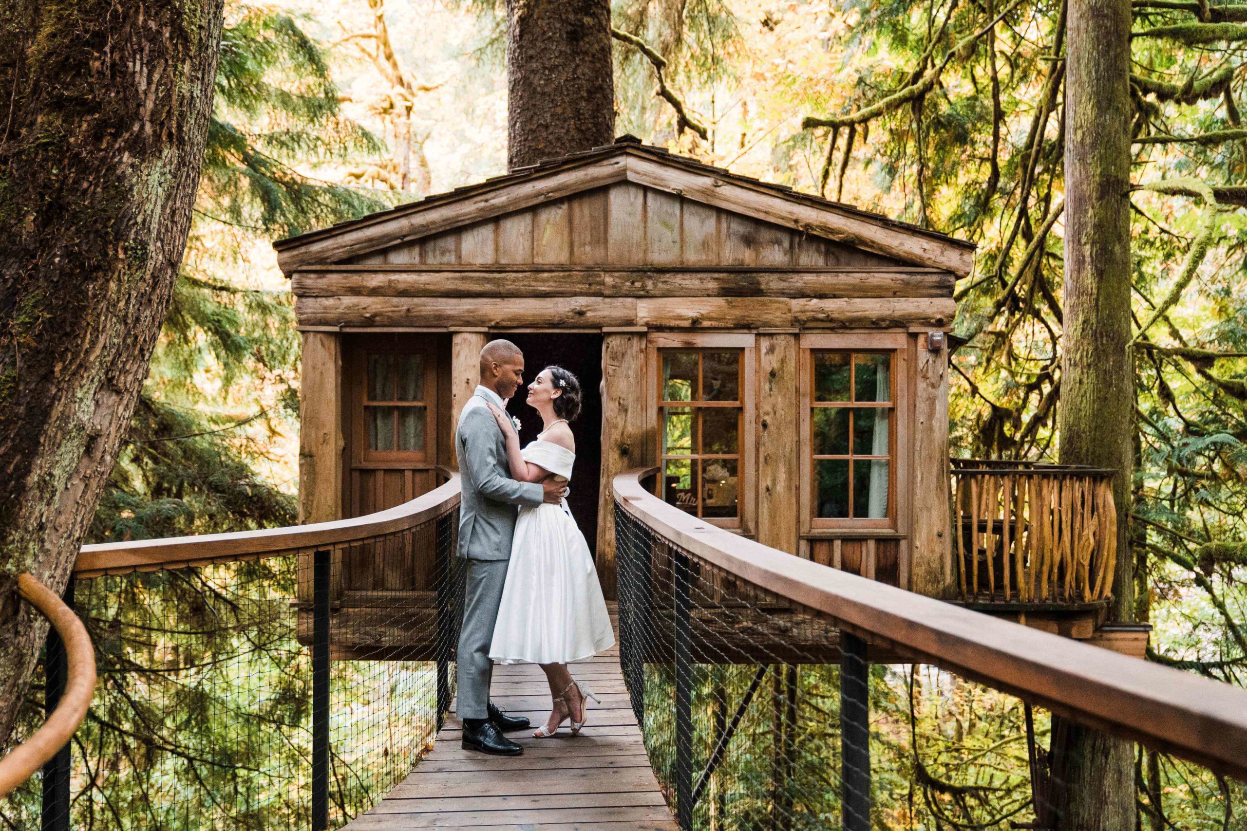 Bride and groom standing in front of the cabin at Treehouse Point for couple photos