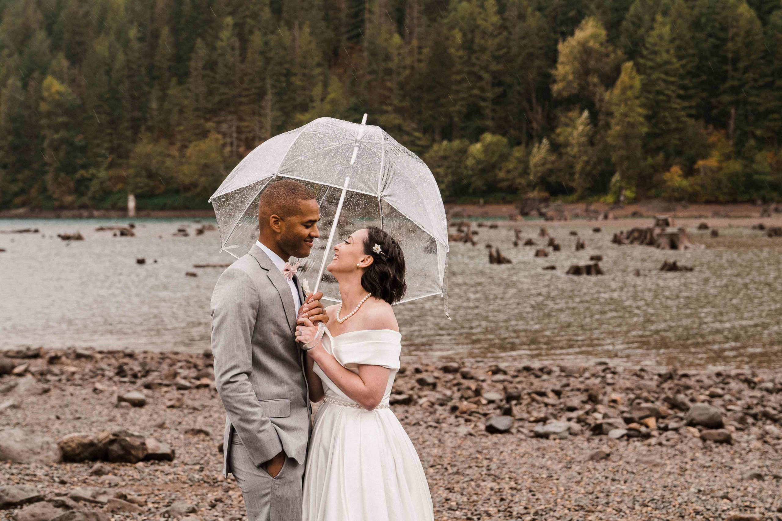 Bride and groom standing under a clear umbrella for their couple photos at Rattlesnake Lake