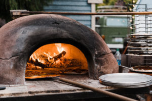 Wood fire pizza oven at backyard wedding reception