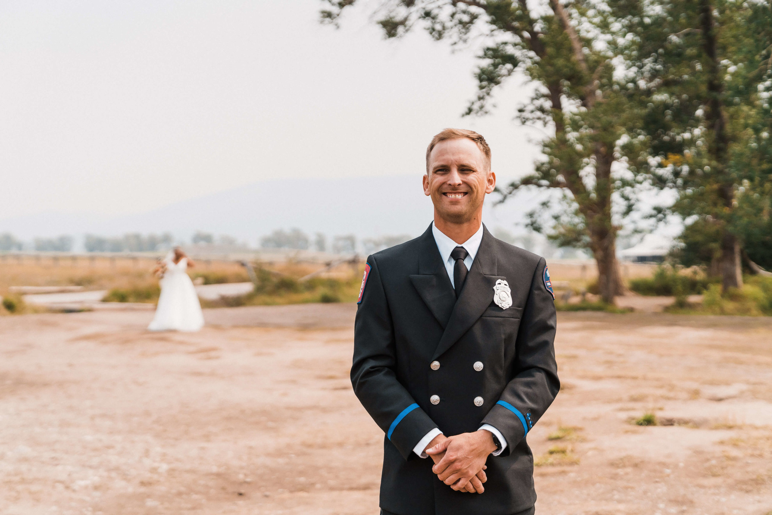 Groom in uniform smiling while waiting for bride for their first look