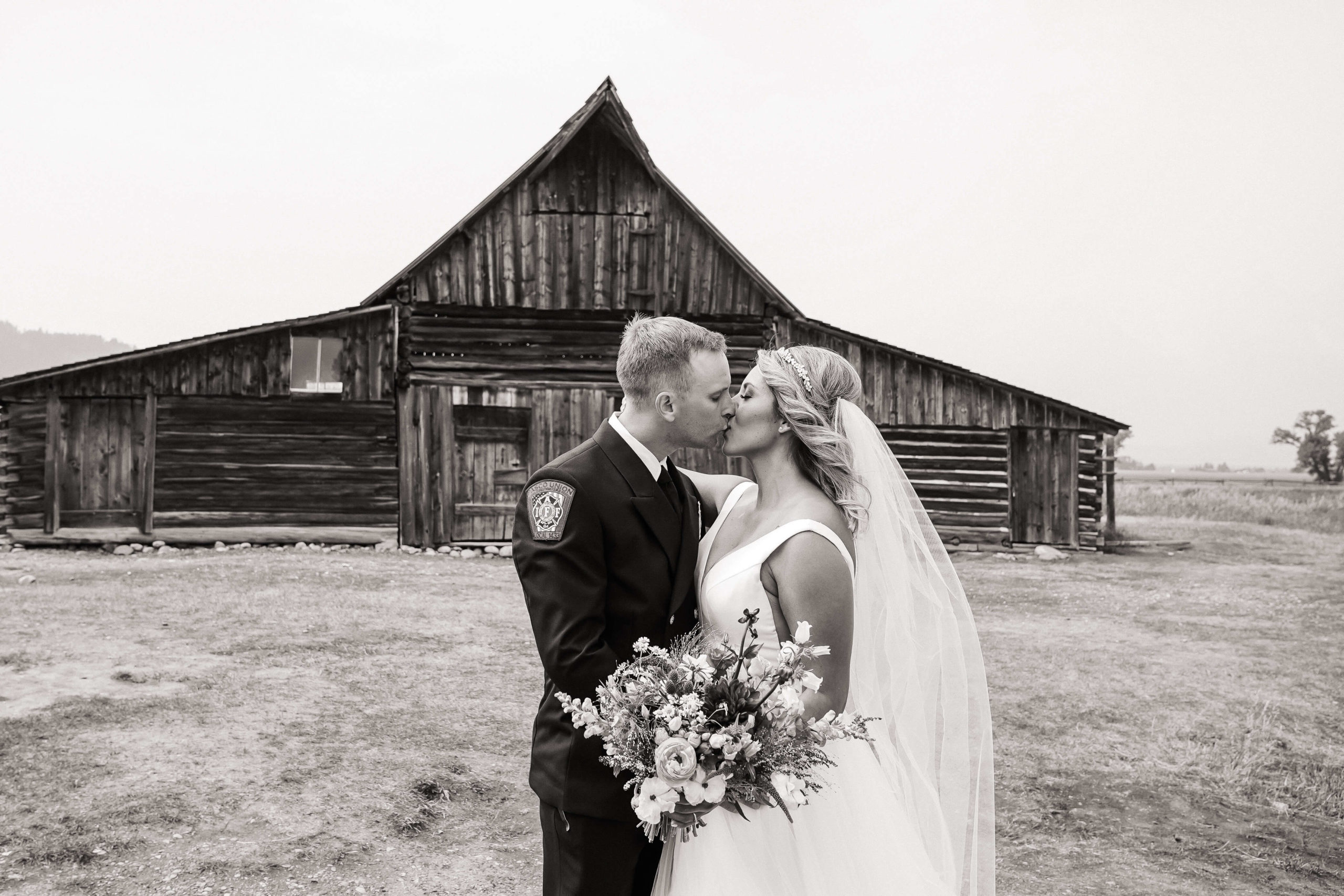 Bride and groom kiss in front of a barn in Jackson Hole, Wyoming