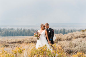 Bride and groom standing in a field for couple photos at small summer wedding