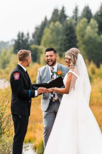 Groom putting ring on bride's finder during wedding ceremony at Grand Teton National Park