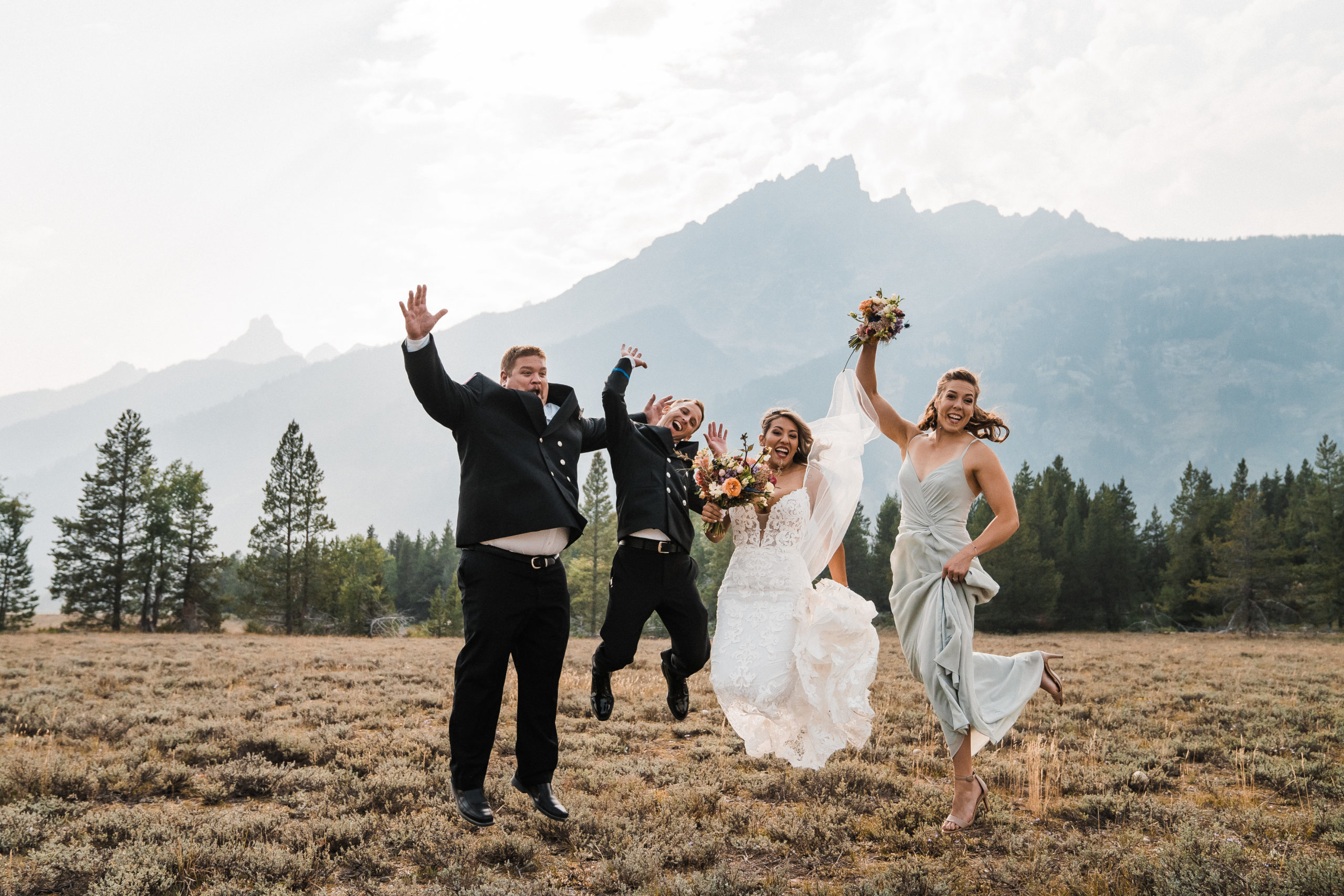 Bride, groom, best man, and maid of honor jumping into the air after small summer wedding ceremony