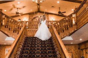 Bride walking down grand wood staircase at a mountain lodge for her small wedding ceremony