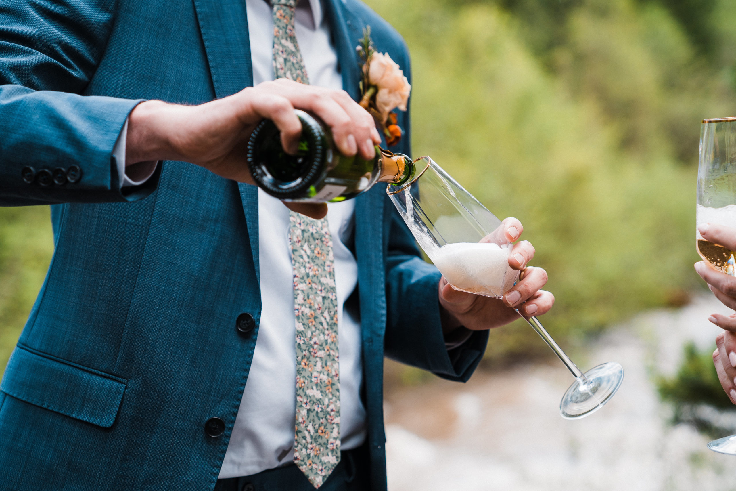 Groom pouring champagne during hiking wedding in Oregon
