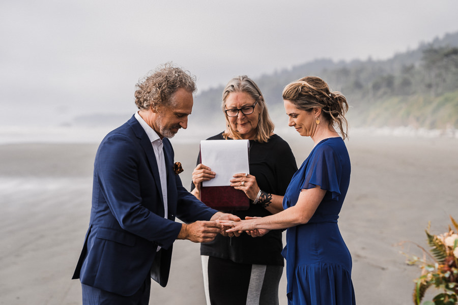 Groom gives his bride her ring during a coastal elopement ceremony