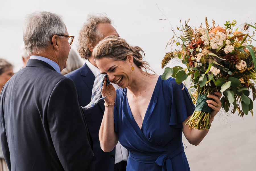 Bride uses her dad's tie to wipe tears after her wedding ceremony on the Washington coast