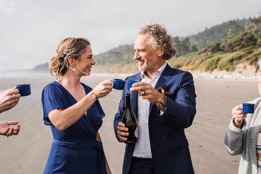 Bride and groom toast with mini camp mugs on Kalaloch Beach after their elopement