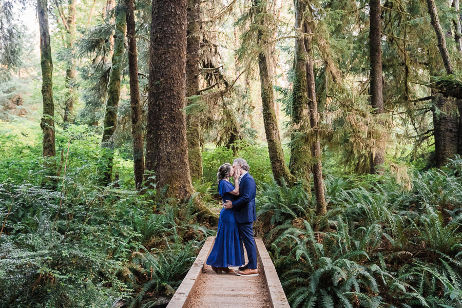 Bride and groom kiss on a bridge in Olympic National Park's mossy forest