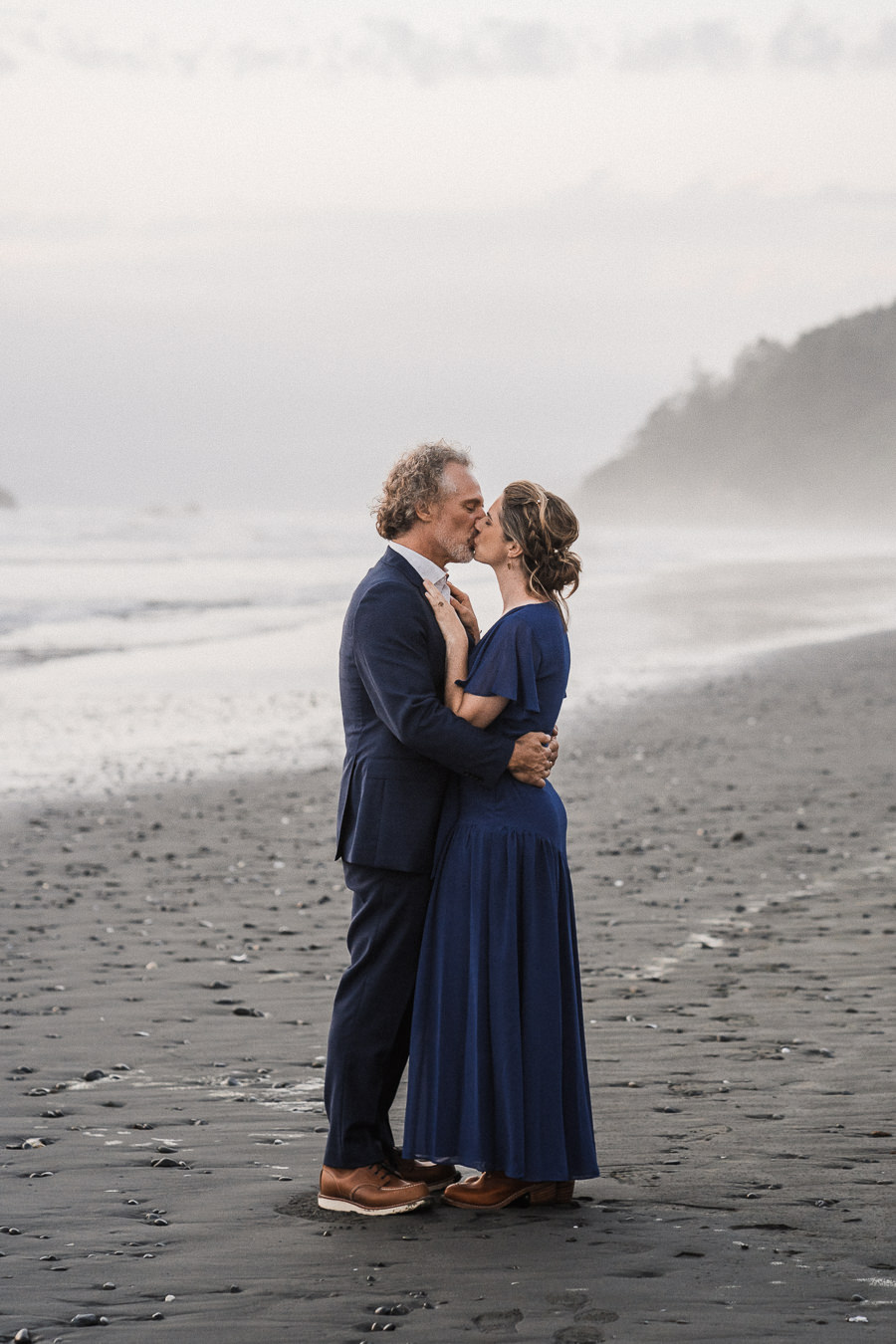 Bride and groom share a kiss on the misty beaches of Washington after their coastal elopement