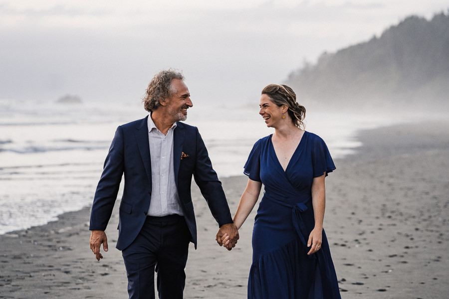 Bride and groom walk along a misty Pacific Northwest beach in Olympic National Park