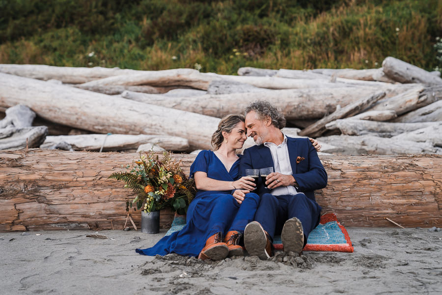 Bride and groom snuggle close and share a beer after their Olympic National Park elopement on Kalaloch Beach