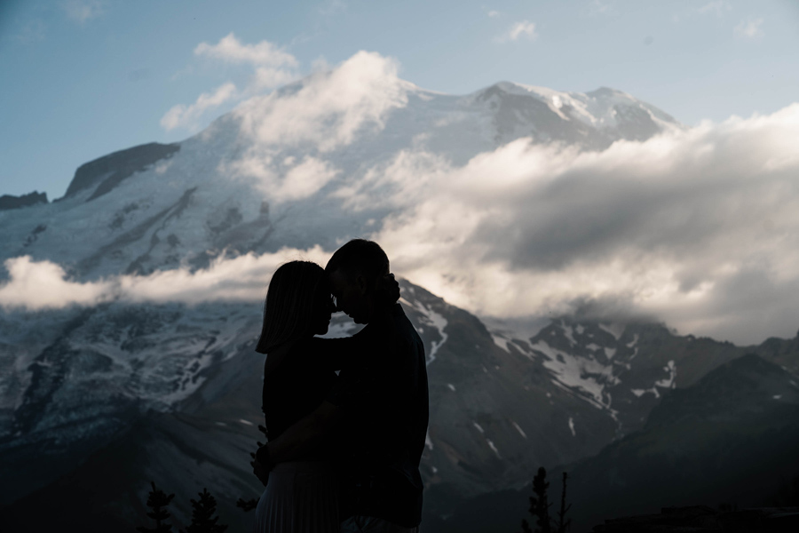 a couple is silhouetted agains a majestic backdrop of Mt rainier in washington state