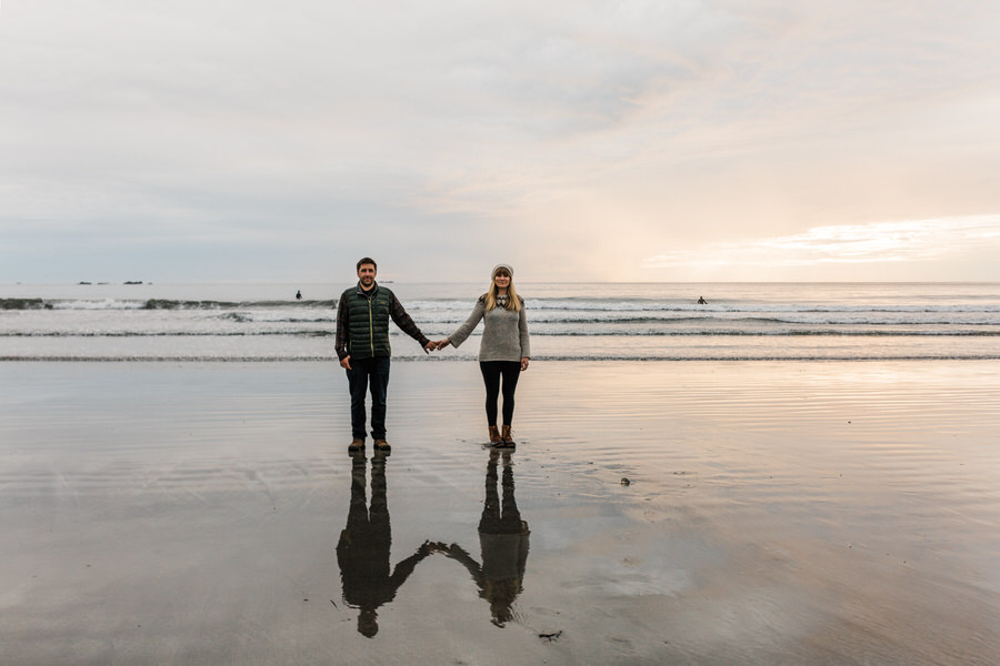 A couple holds hands with the Pacific Ocean in the background on the coast of Washington