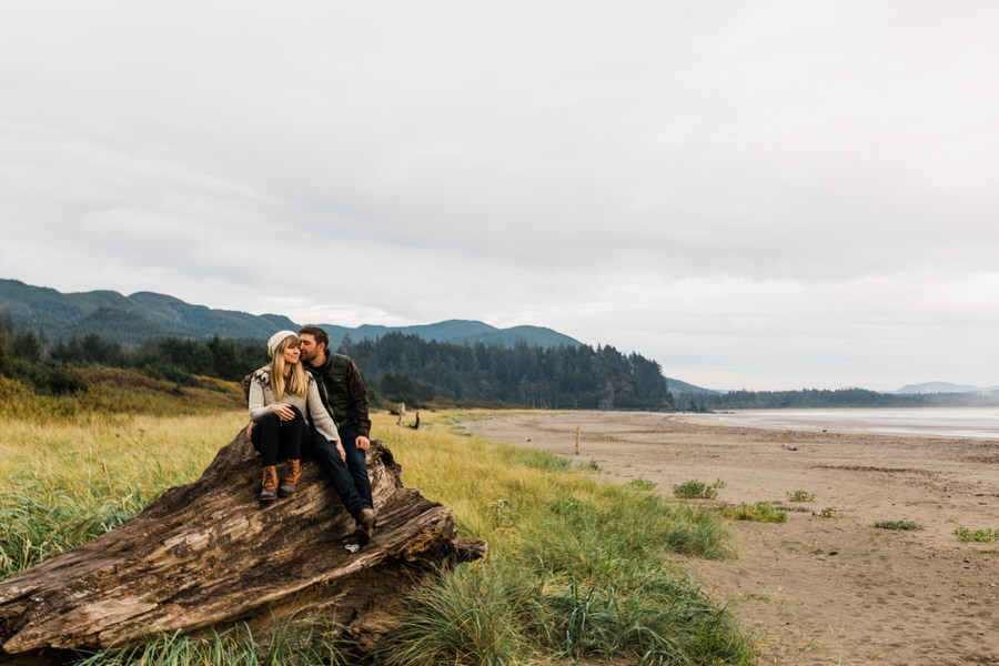 A couple sits on a giant fallen log on Washington's north coast