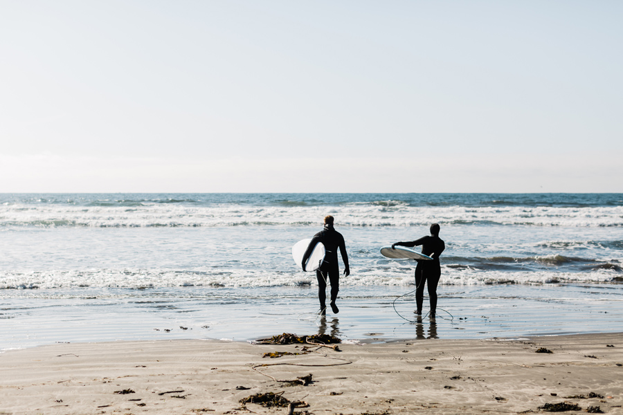 a couple walks into the Pacific Ocean in Washington with their surfborads