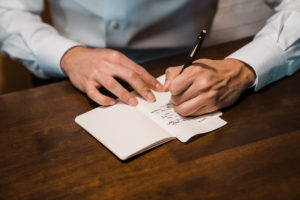 A groom writes his vows in a small book